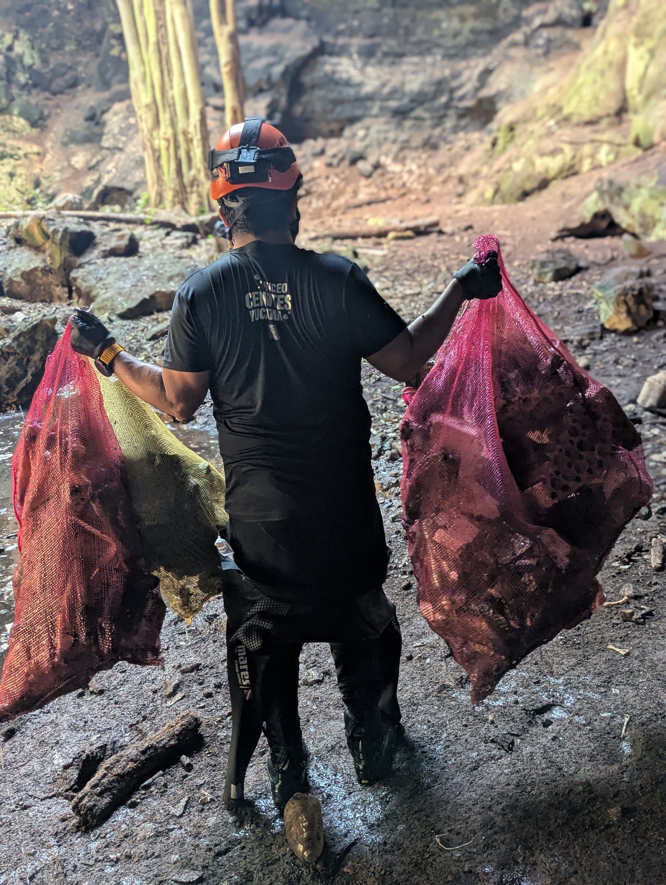 Especialista transportando bolsas con residuos recuperados de un cenote